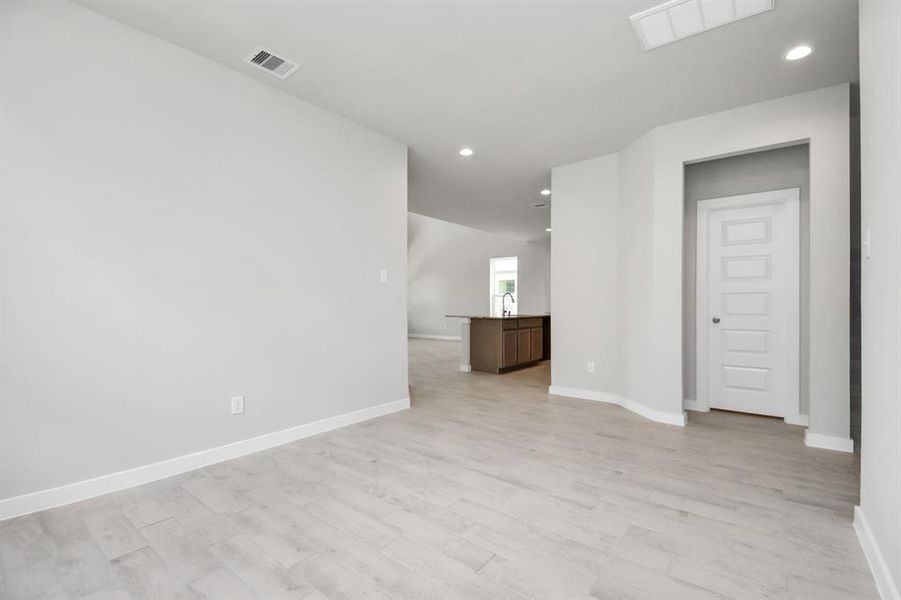 This expansive dining room showcases sophisticated flooring, custom paint, and seamlessly connects to the family room and kitchen, providing an open and inviting atmosphere. Sample photo of completed home. Actual colors and selections may vary.