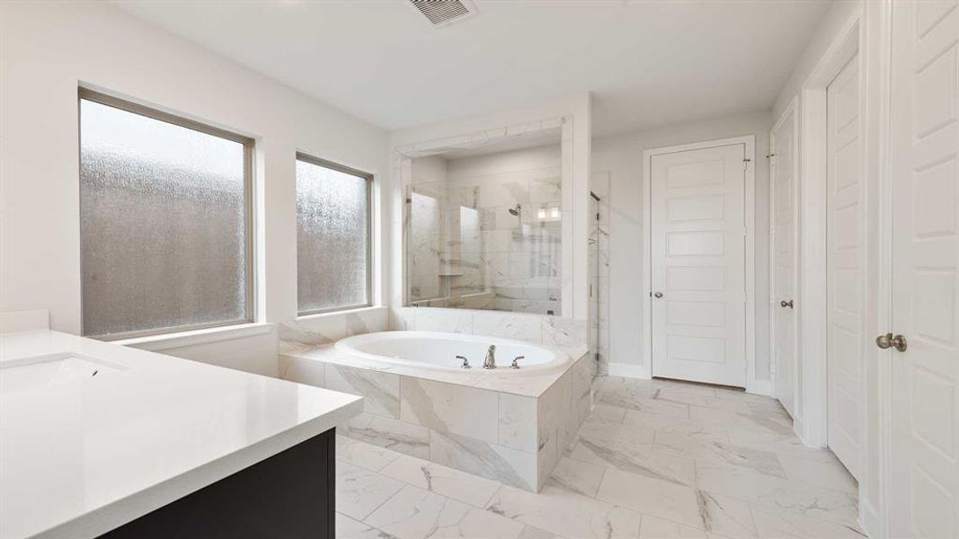 Bathroom featuring plus walk in shower, a wealth of natural light, and vanity