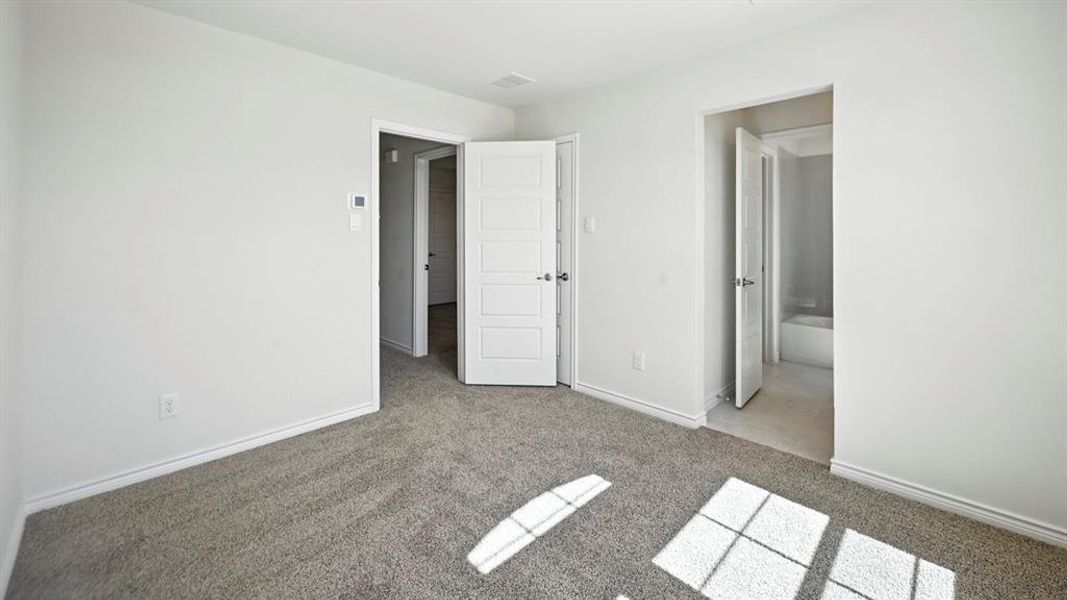 Unfurnished bedroom with light colored carpet and ensuite bath Unfurnished bedroom with light colored carpet and ensuite bath