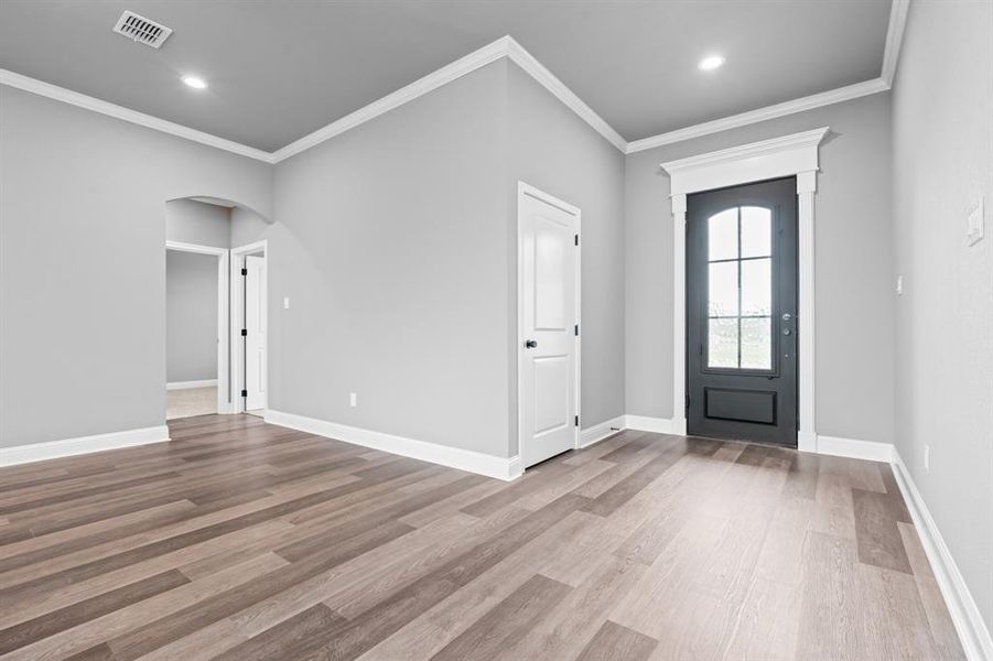 Entrance foyer with wood finished floors, ornamental molding, visible vents, recessed lighting, and arched walkways Entrance foyer with wood finished floors, ornamental molding, visible vents, recessed lighting, and arched walkways
