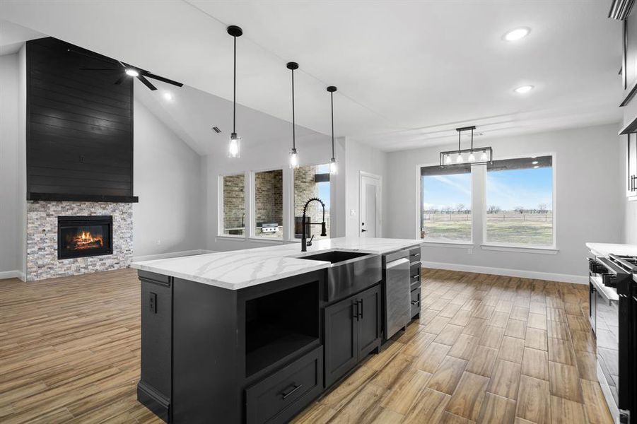 Kitchen with a large island, ceiling fan, stainless steel appliances, hanging light fixtures, and a fireplace