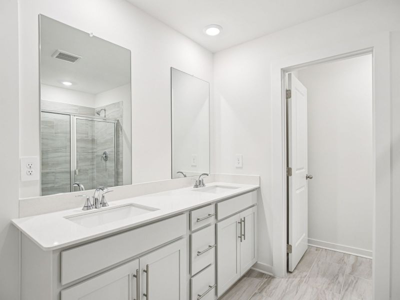 The primary bathroom offers dual vanity sinks and a walk-in shower.