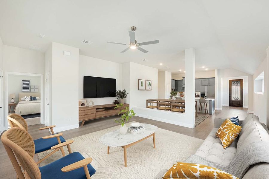 Open-concept living room with ceiling fan, wall-mounted TV, gray sofa, and view into dining area and kitchen