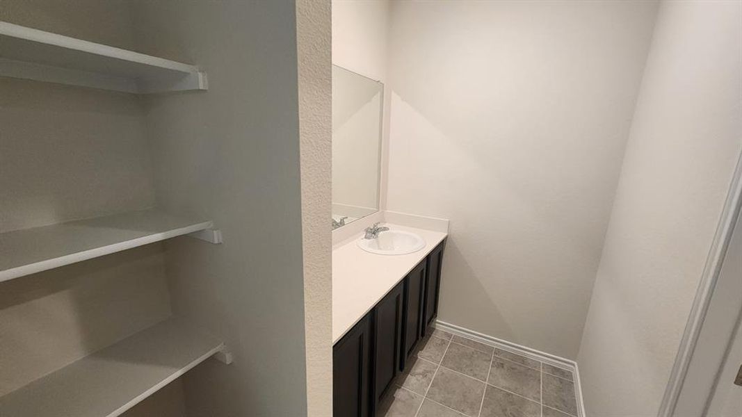 Vanity with a white countertop and integrated sink, dark wood-finish cabinetry, and a framed mirror Vanity with a white countertop and integrated sink, dark wood-finish cabinetry, and a framed mirror