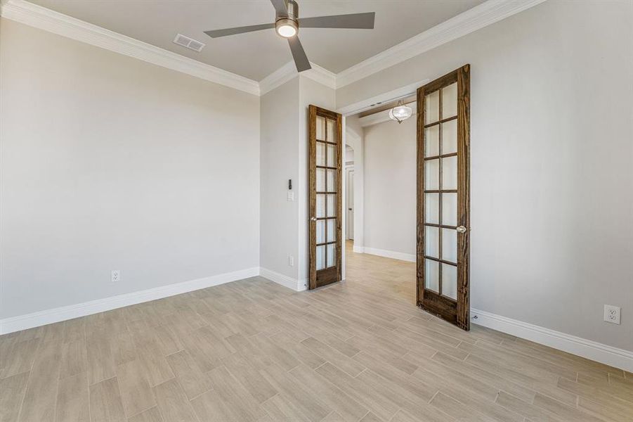 Unfurnished room featuring french doors, wood finish floors, ornamental molding, and a ceiling fan