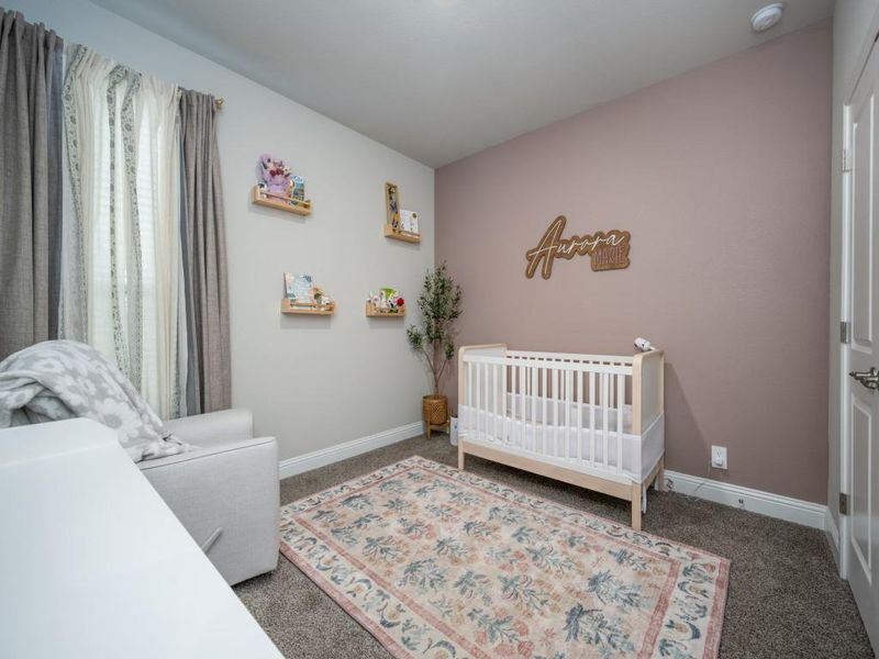 Delightful third bedroom features a soft pink accent wall that adds a touch of warmth and personality.