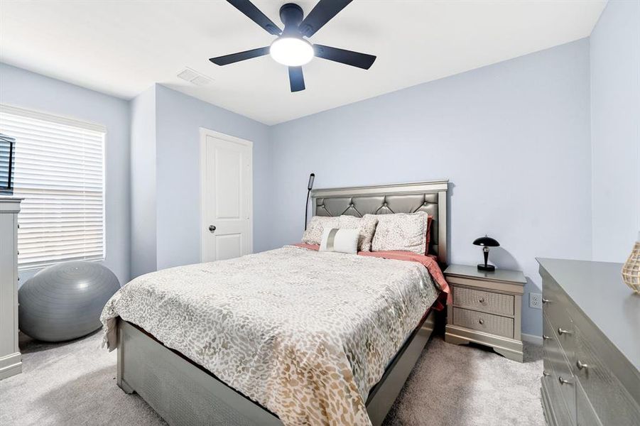 Bedroom featuring light blue wall paint, gray carpet flooring, and a ceiling fan with integrated lighting