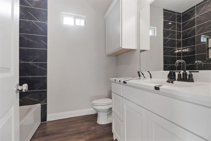 Full bathroom with vanity, toilet, tiled shower / bath, and hardwood / wood-style flooring