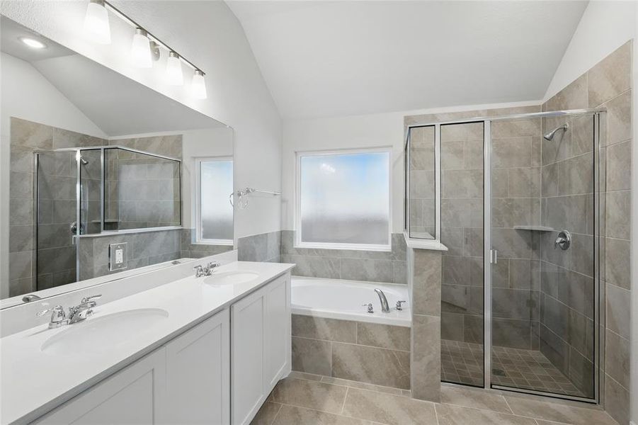 Bathroom featuring vaulted ceiling, double vanity, a bath, light tile patterned floors, and a stall shower Bathroom featuring vaulted ceiling, double vanity, a bath, light tile patterned floors, and a stall shower