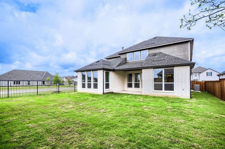 Rear view of property featuring brick siding, a patio area, a fenced backyard, a residential view, and a shingled roof