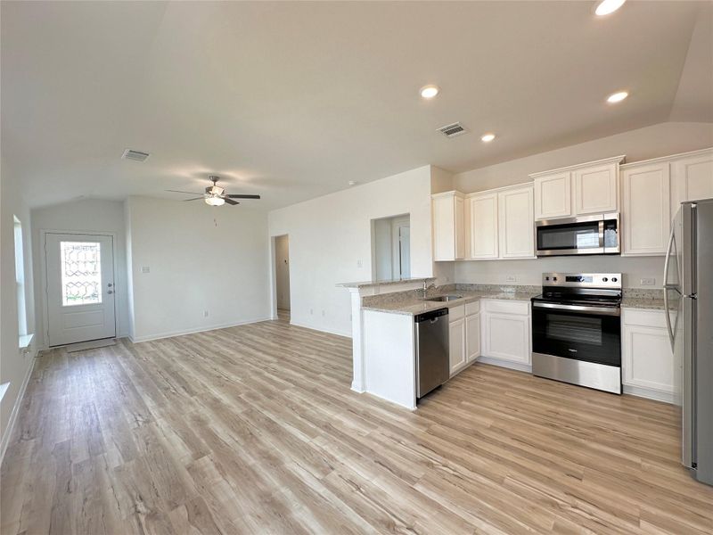 Kitchen includes granite countertops, luxury vinyl plank flooring, 36” upper cabinets with crown molding, a full suite of stainless-steel Whirlpool appliances – including refrigerator with ice maker, recessed lighting, and a large single basin sink.