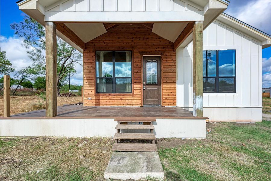 Natural wood accents line the covered front porch of this modern board-and-batten home.