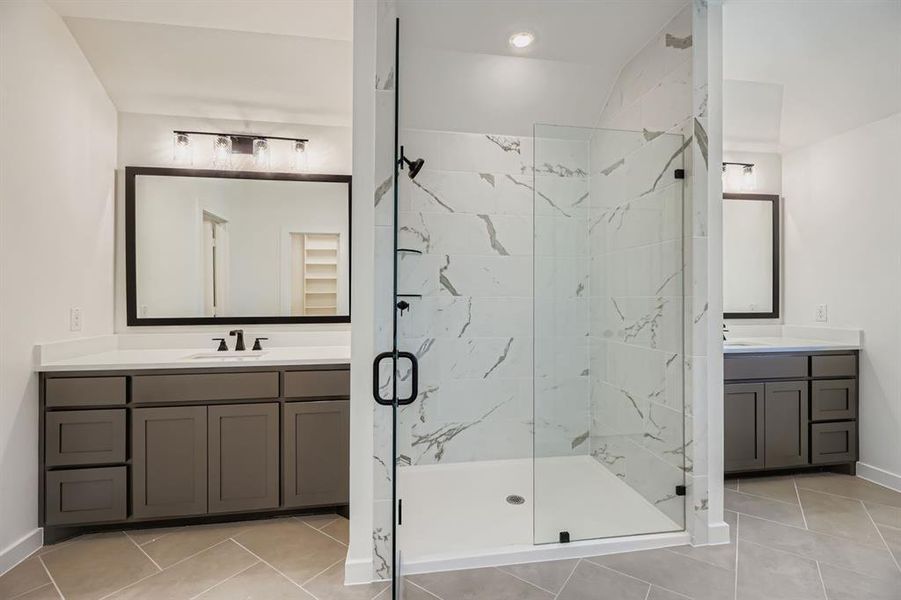 Bathroom with a marble finish shower, two vanities, light tile patterned floors, and recessed lighting