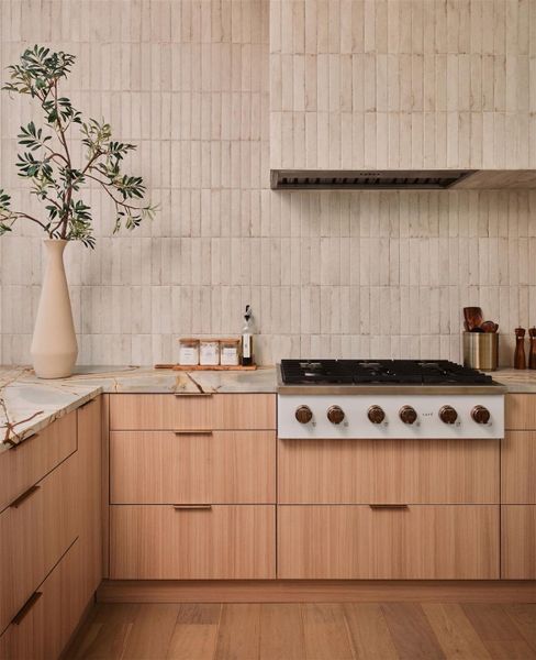 Kitchen with white gas cooktop, modern cabinets, light wood finish cabinets, backsplash, and light wood-type flooring