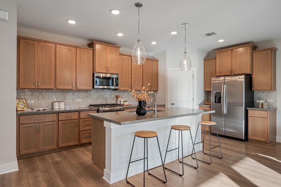 The kitchen features stainless-steel appliances, a gas stove, a refrigerator, and a large quartz island.