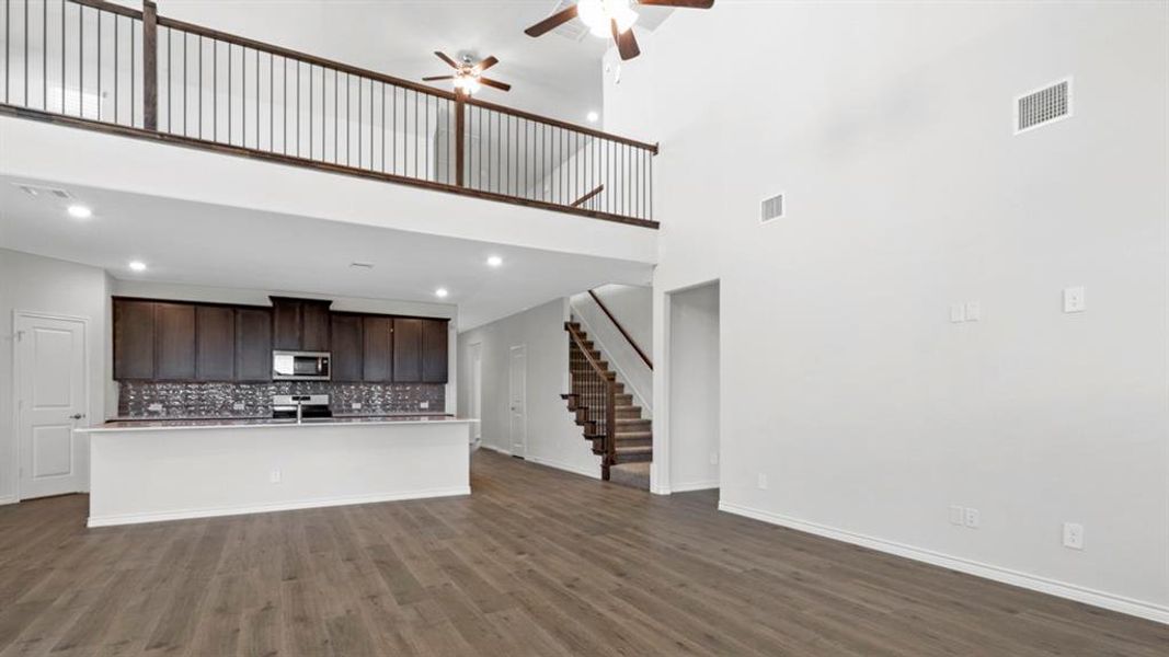Open-concept living area featuring high ceilings, wood-finish flooring, and recessed lighting