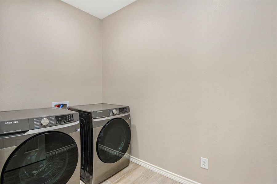 Laundry area with washer and dryer and light wood-style floors