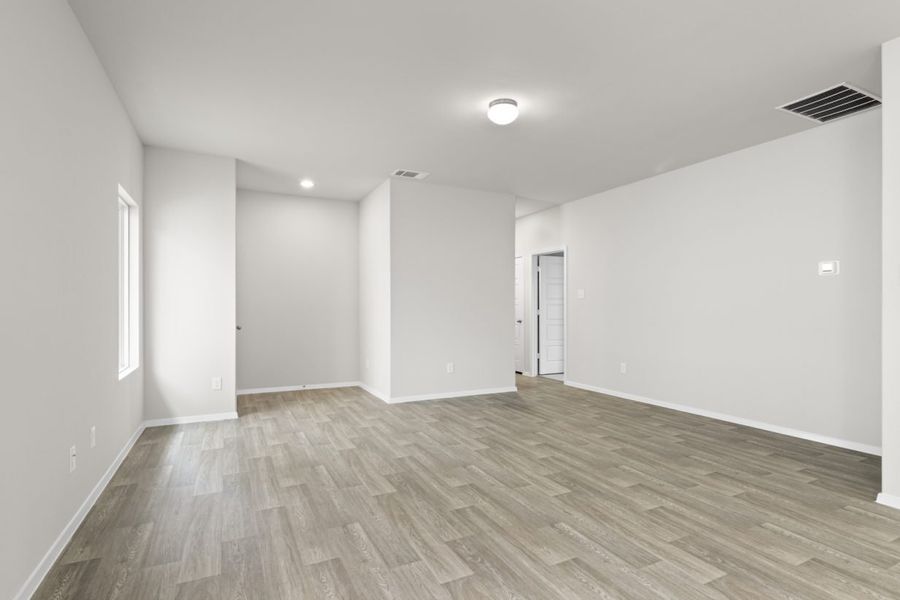 Image of a living room with cream walls, light brown vinyl flooring, a window and a white front door