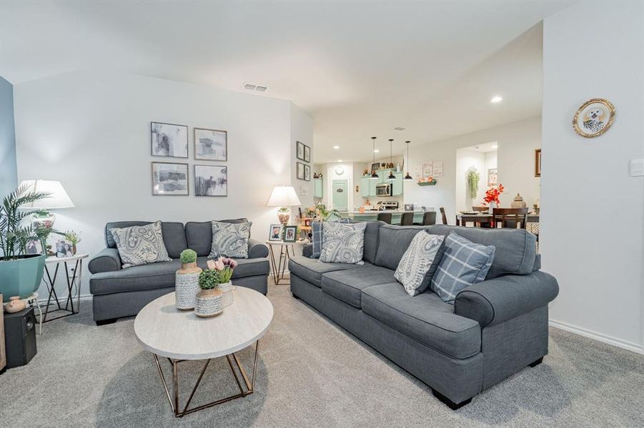 Living area with recessed lighting, visible vents, baseboards, and light colored carpet