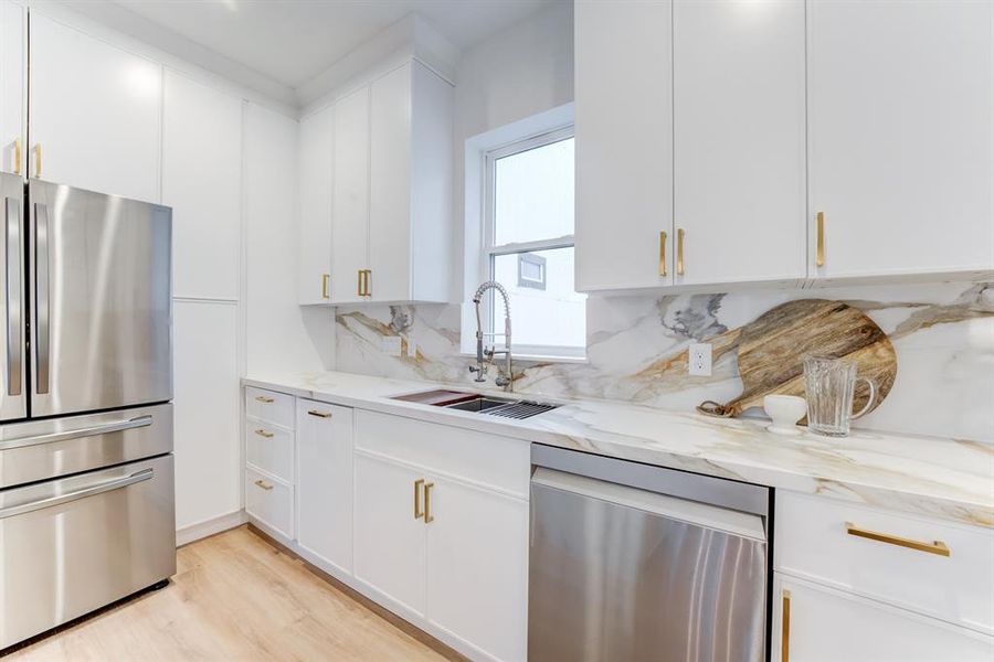 The home includes stainless steel appliances, pantry storage, and stunning white cabinetry and drawers for a timeless kitchen space.