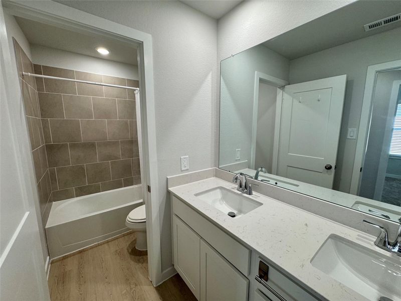 Upstairs bathroom featuring a spacious vanity with dual sinks, large mirror, and a tub/shower combination. Upstairs bathroom featuring a spacious vanity with dual sinks, large mirror, and a tub/shower combination.