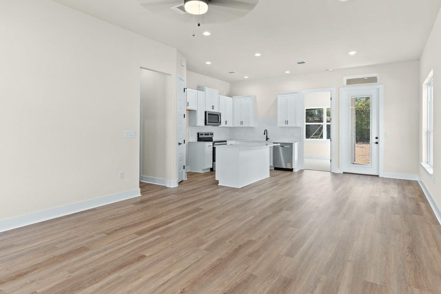 Kitchen with open floor plan, white cabinetry, a center island, appliances with stainless steel finishes, and tasteful backsplash