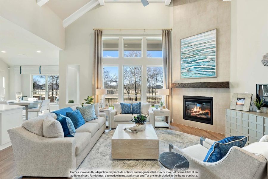 Living room with vaulted ceiling, tile fireplace, large windows, and neutral sofas with blue accent pillows Living room with vaulted ceiling, tile fireplace, large windows, and neutral sofas with blue accent pillows