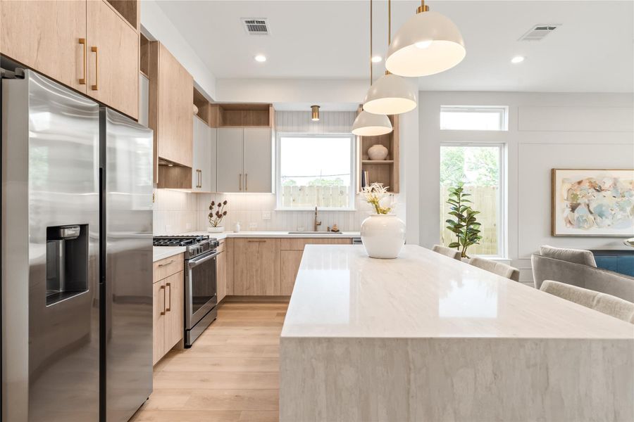 The waterfall quartz island is the true anchor of this kitchen, offering serious counter space and room for seating without breaking up the room's flow. It's built for both quick mornings and slower gatherings.