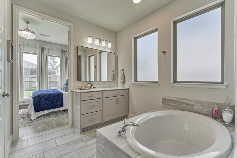 Dual vanities with brushed gold pulls, framed mirrors, garden tub and separate large walk-in shower.