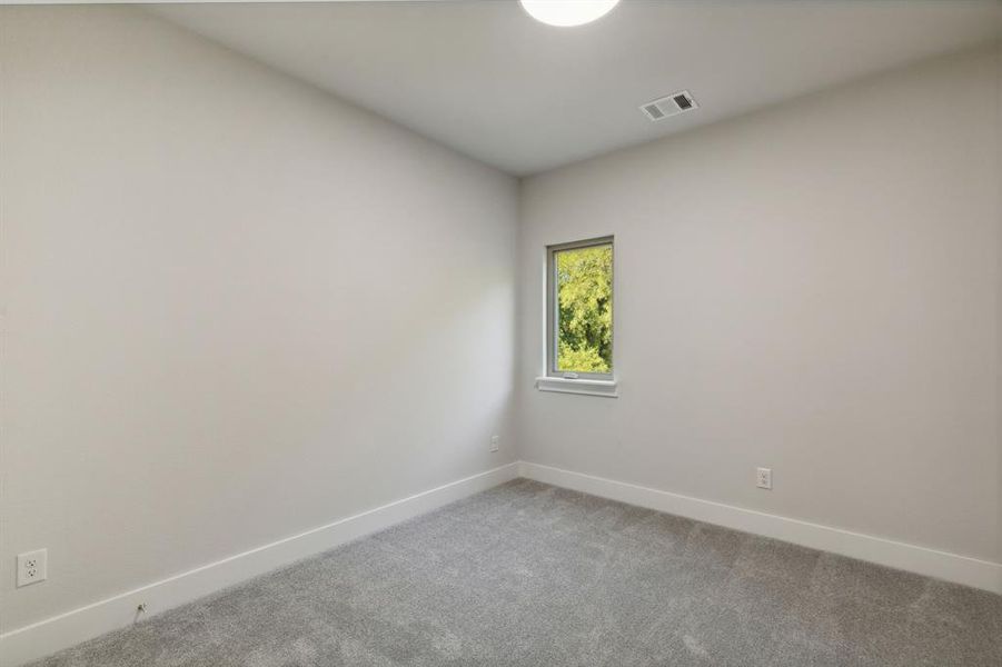 Unfurnished secondary room featuring baseboards, visible vents, and light colored carpet