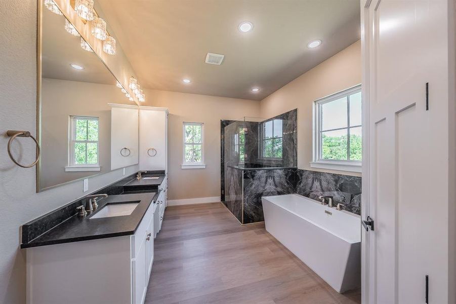 Primary bath features stand alone tub, beautiful enclosed shower, and dual vanities with granite countertops.
