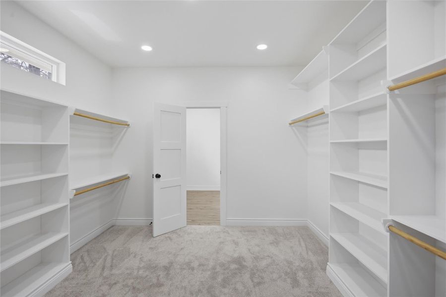 Oversized primary closet featuring built-in shelving and convenient laundry access.