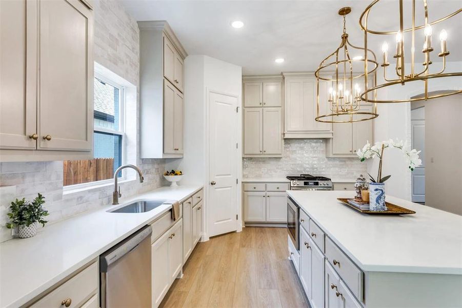 Kitchen with pendant lighting, decorative backsplash, appliances with stainless steel finishes, recessed lighting, and light wood-style flooring Kitchen with pendant lighting, decorative backsplash, appliances with stainless steel finishes, recessed lighting, and light wood-style flooring