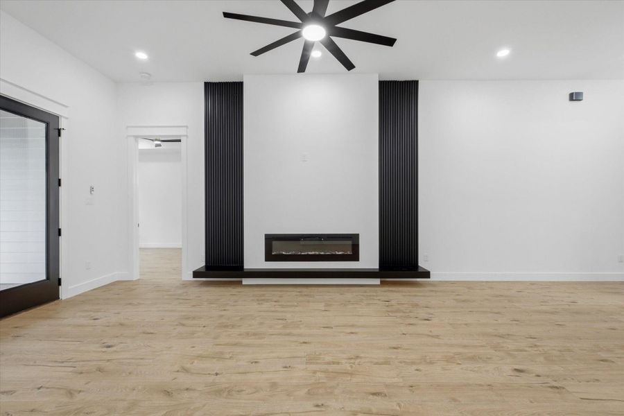 A Dramatic Focal Point. Cozy up in style! This striking living room accent wall features a sleek, flush-mount electric fireplace set beneath a crisp white media wall, perfectly framed by bold, contemporary black vertical slat panels.
