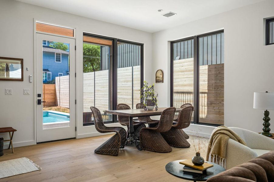 Sunlight streams through expansive windows across rich hardwood floors.