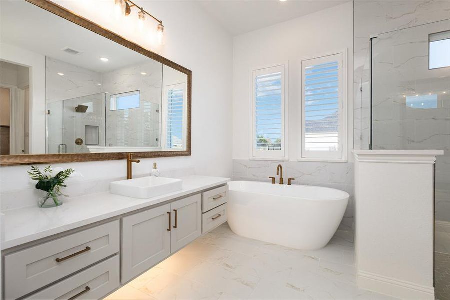 Full bath with a marble finish shower, vanity, a freestanding tub, light marble finish flooring, and recessed lighting