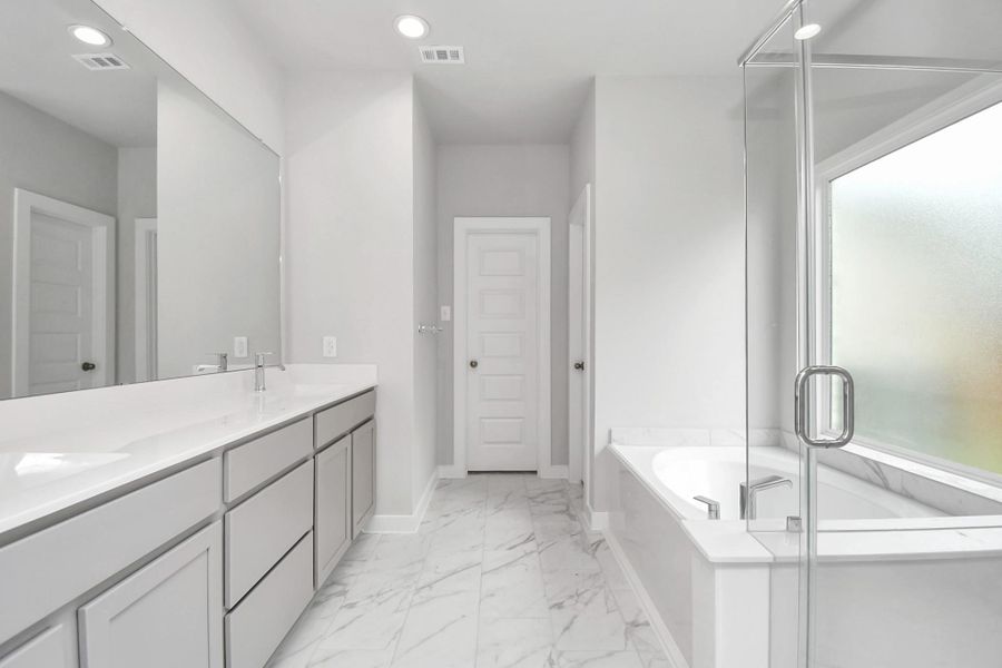 Experience luxury in this spa-like primary bathroom featuring a massive walk-in shower with tile surround. Light colored cabinets with light granite countertops complement the space, alongside a spacious walk-in closet with shelving, high ceilings, custom paint, and sleek, dark modern finishes. An ideal retreat for unwinding after a long day. Sample photo of completed home with similar floor plan. As-built interior colors and selections may vary. Experience luxury in this spa-like primary bathroom featuring a massive walk-in shower with tile surround. Light colored cabinets with light granite countertops complement the space, alongside a spacious walk-in closet with shelving, high ceilings, custom paint, and sleek, dark modern finishes. An ideal retreat for unwinding after a long day. Sample photo of completed home with similar floor plan. As-built interior colors and selections may vary.