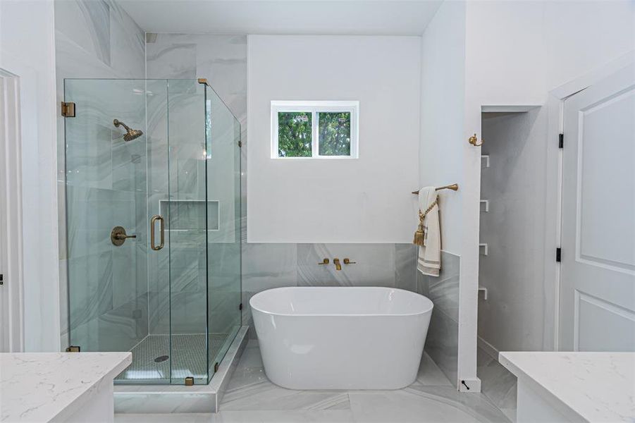 Bathroom featuring vanity, a marble finish shower, a soaking tub, marble finish floors, and tile walls
