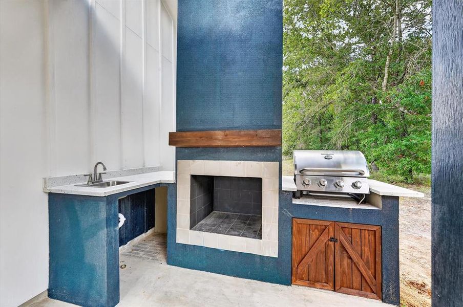 Outdoor kitchen featuring a built-in grill, integrated sink, and ample countertop space