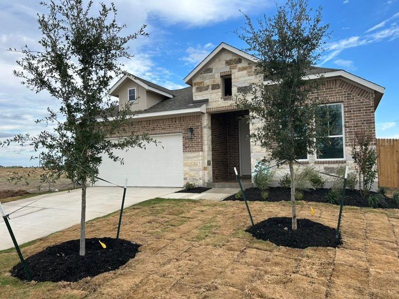 View of front of house featuring stone siding, concrete driveway, and brick siding