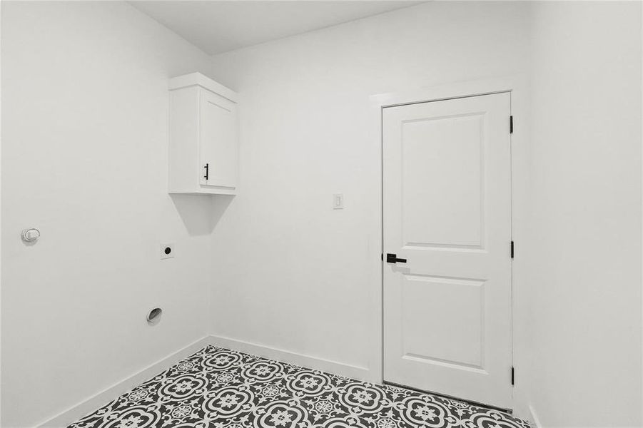 Laundry room with tile patterned flooring, electric dryer hookup, and cabinets