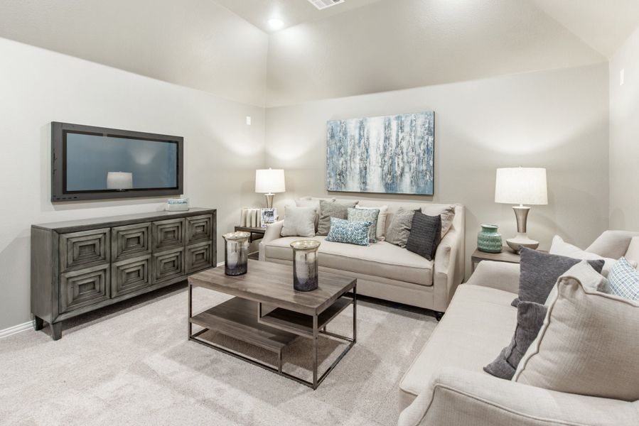 Living room with vaulted ceiling, wall-mounted TV, neutral sofas, and wood coffee table on carpet