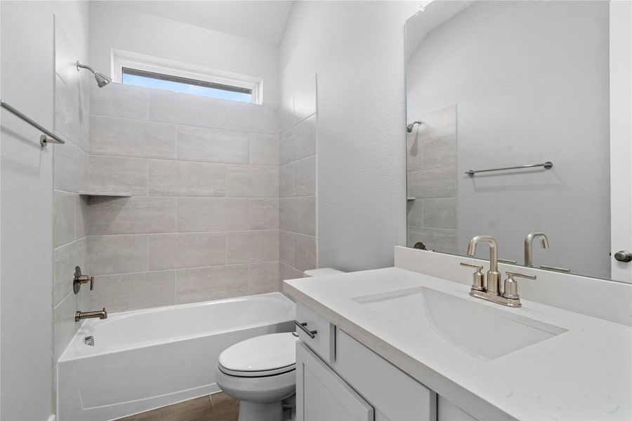 A streamlined secondary bathroom providing a functional tub/shower combination, vanity with modern fixtures seamlessly blending practicality and style.