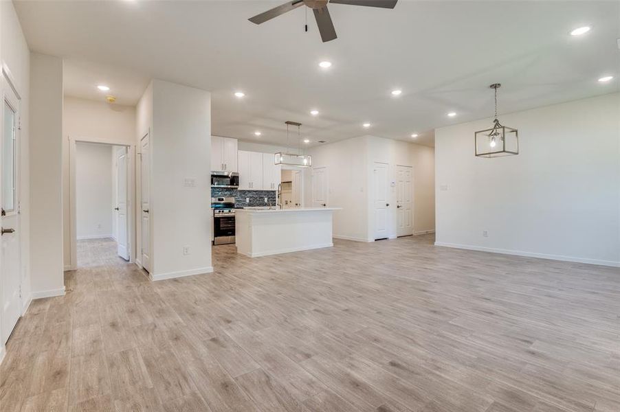 Kitchen featuring backsplash, an island with sink, decorative light fixtures, white cabinets, and recessed lighting