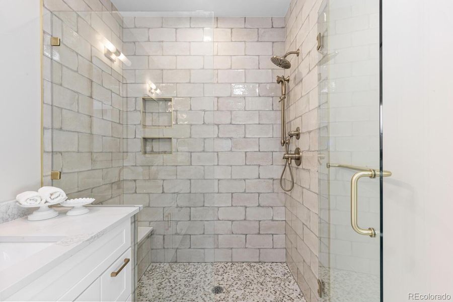 Primary bathroom with double vanities, customtile, glass enclosure, and tubular skylight Primary bathroom with double vanities, customtile, glass enclosure, and tubular skylight