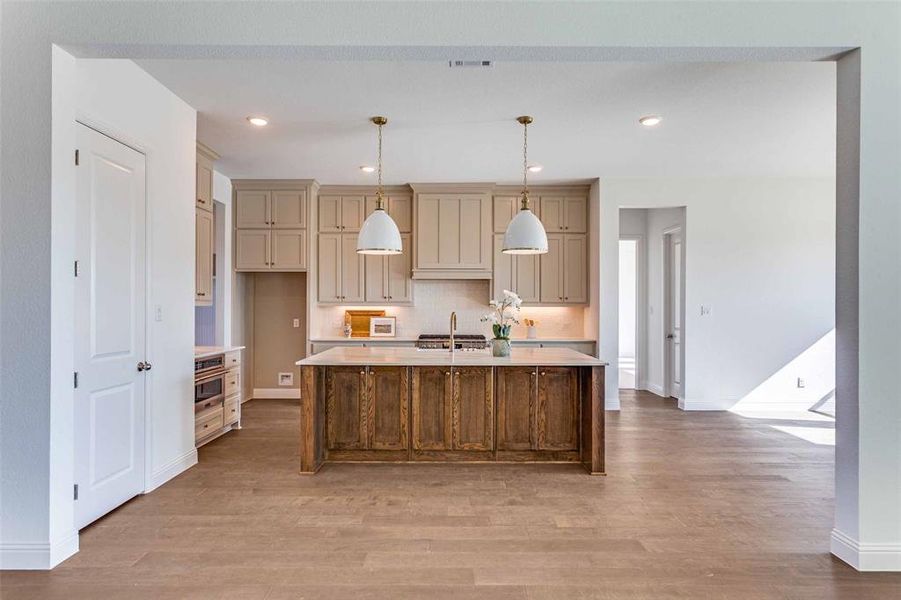 Kitchen featuring decorative light fixtures, cream cabinetry, a kitchen island with sink, recessed lighting, and light wood finished floors Kitchen featuring decorative light fixtures, cream cabinetry, a kitchen island with sink, recessed lighting, and light wood finished floors