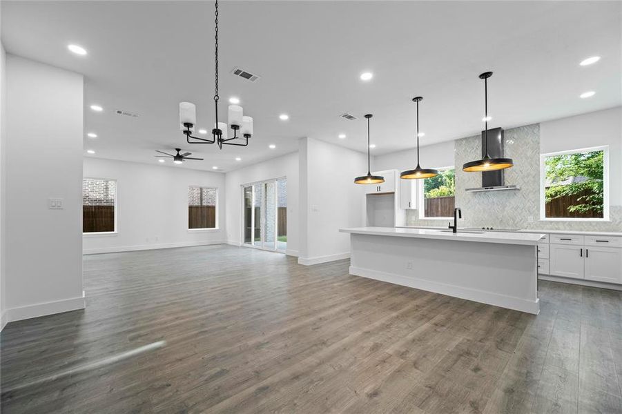 Unfurnished living room with recessed lighting, healthy amount of natural light, wood finished floors, a chandelier, and a ceiling fan Unfurnished living room with recessed lighting, healthy amount of natural light, wood finished floors, a chandelier, and a ceiling fan