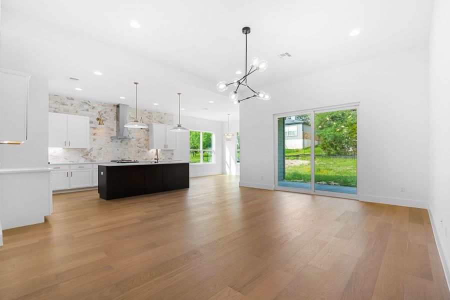 Unfurnished living room featuring sink, a notable chandelier, and light wood-type flooring Unfurnished living room featuring sink, a notable chandelier, and light wood-type flooring