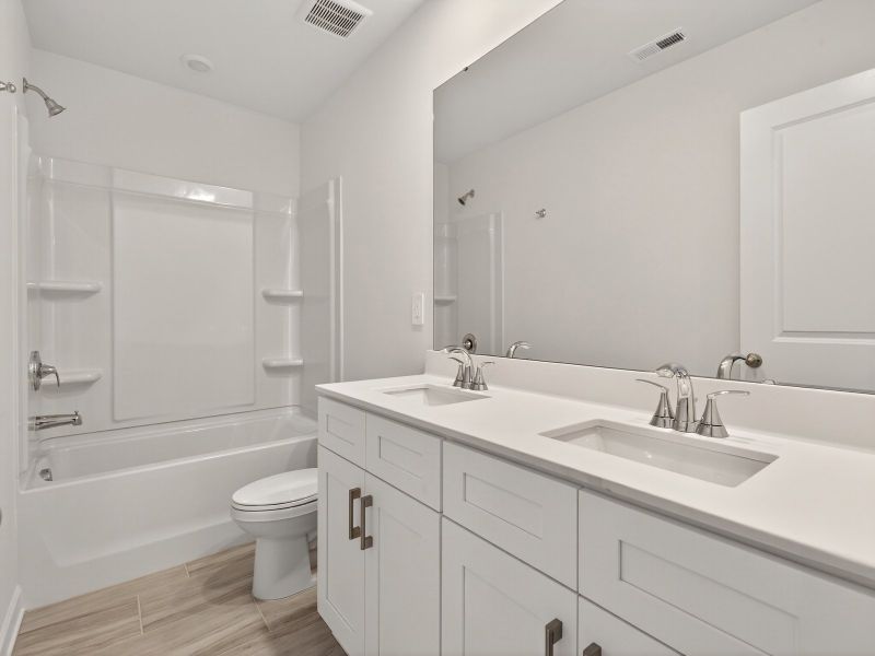 The secondary bathroom features a dual-sink vanity and oversized shower tub.
