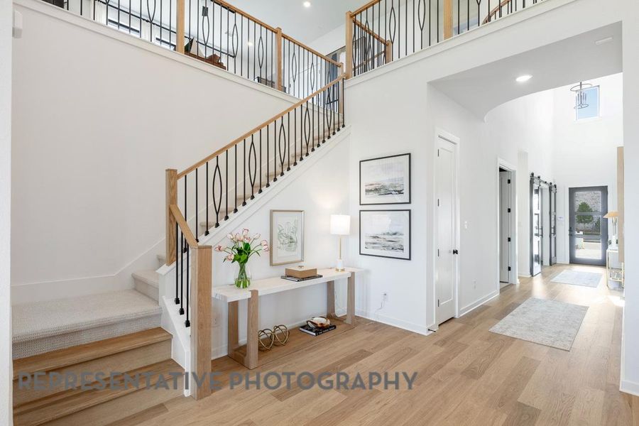 Stairs featuring a towering ceiling, wood finished floors, and baseboards